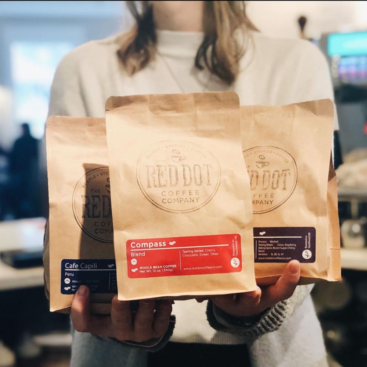 a girl holding three bags of coffee
